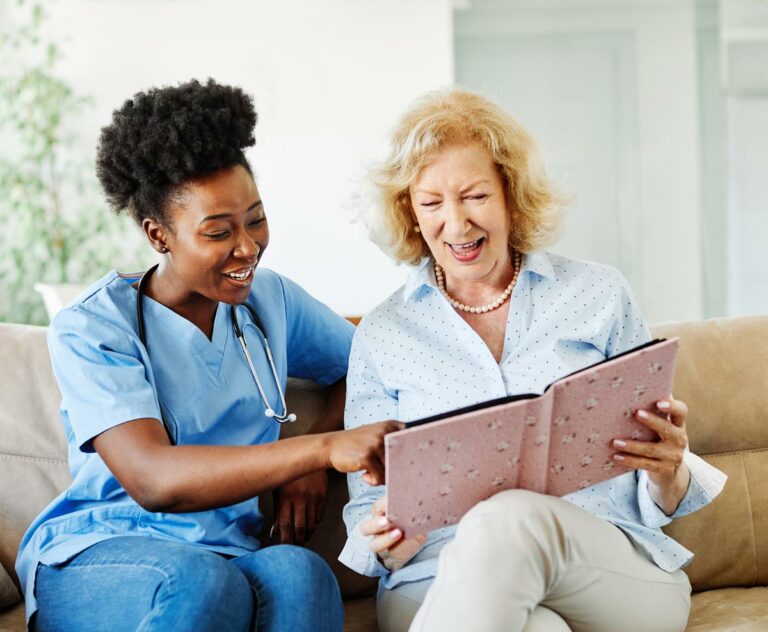 Hillcrest | Senior woman looking at photo album with associate