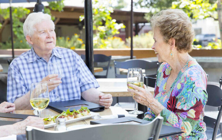 Hillcrest | Senior couple eating and drinking wine on the patio of a restaurant