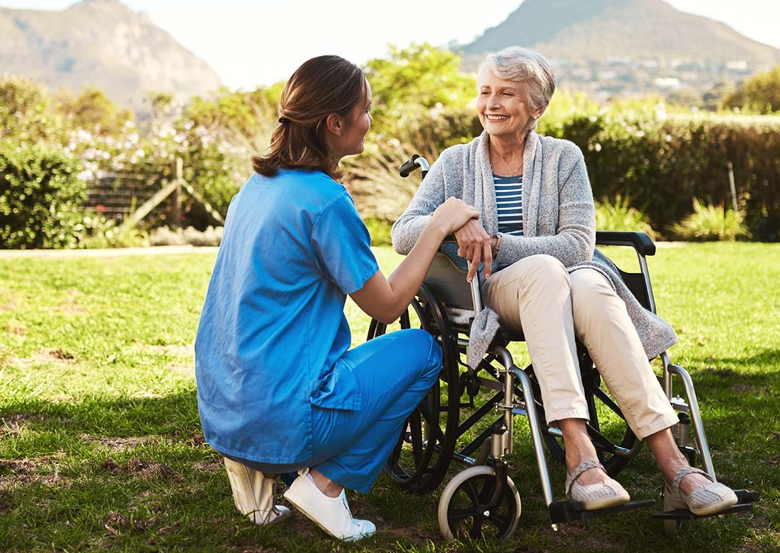 Hillcrest | Happy senior woman sitting outside with caregiver